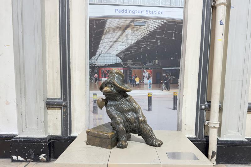 旅行カバンに腰をかけている姿がかわいいパディントンベアの銅像