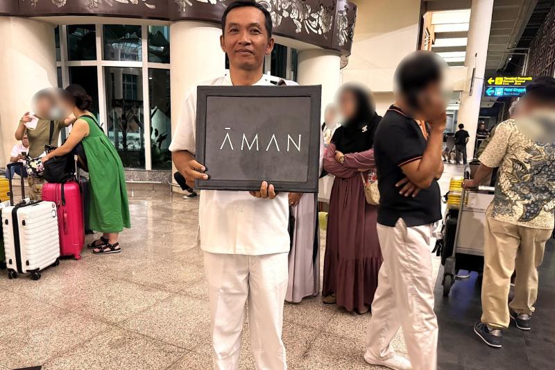 “AMAN”のボードを持ったスタッフ