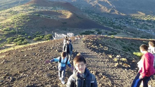 【1】マウナ・ケア山中腹のオニヅカセンターから、近くの丘に登る子供達と研究者のＨ氏