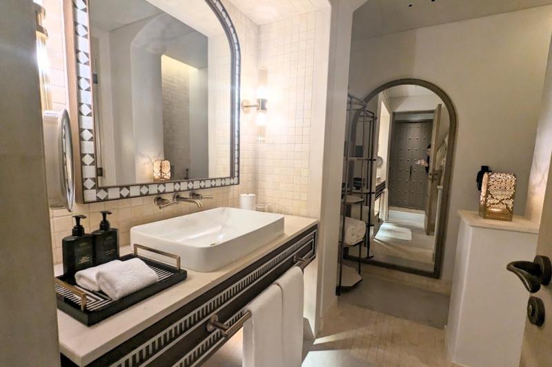 タイルで縁取られた鏡がかわいい、大理石のバスルーム
