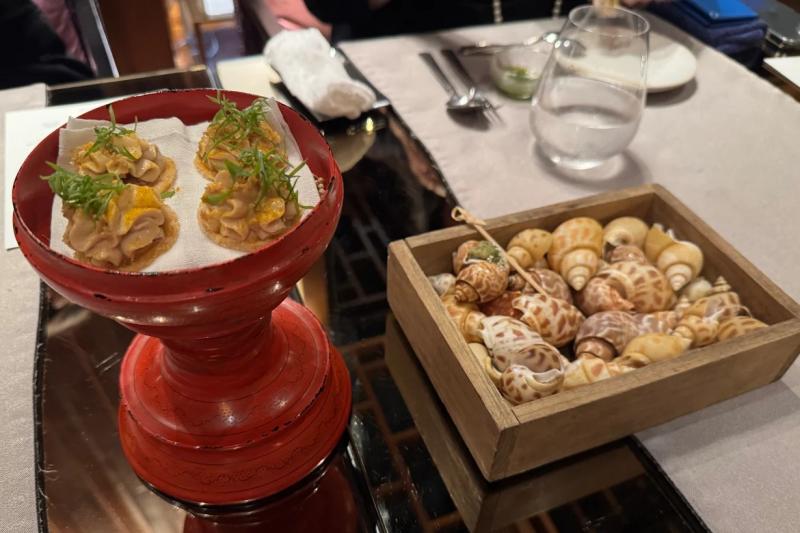 1. 遊び心あふれる前菜左側はマッサマンカレーのひと口前菜で、サクサクの薄いクラッカーのような生地の上に、ピーナッツやココナッツミルクの効いた濃厚なタイカレー風味のムースが絞られ、ハーブがトッピングされています。 右側は「シースネイルキス」と名付けられた前菜で、“海のエスカルゴ”と呼ばれる小さな巻貝をタイ特有のハーブやスパイスで風味豊かに味付けした、遊び心のある一品です
