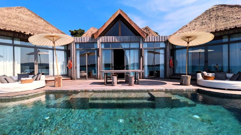 左右にある茅葺屋根の建物にベッドルームがあり、真ん中にリビングのある大型ヴィラ
