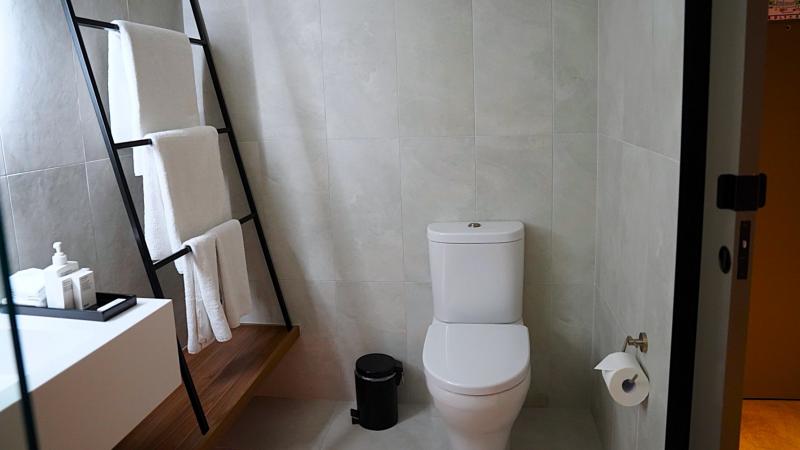 清潔感あふれるトイレと、黒のラダーラックにおしゃれに掛けられたタオル類